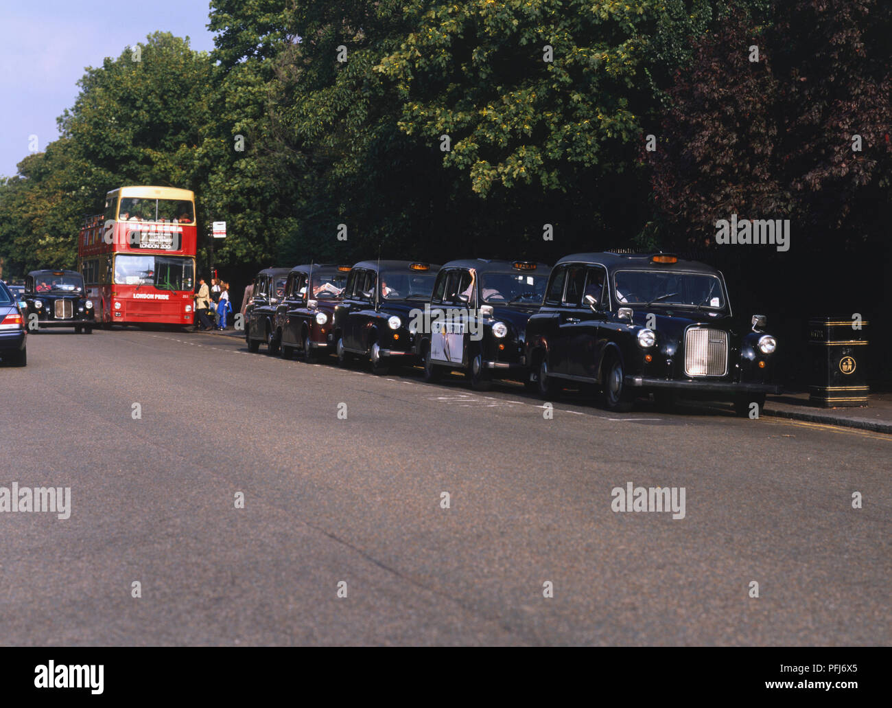 Great Britain, England, London, line of parked black cabs, red open-top sightseeing bus in background, front view. Stock Photo