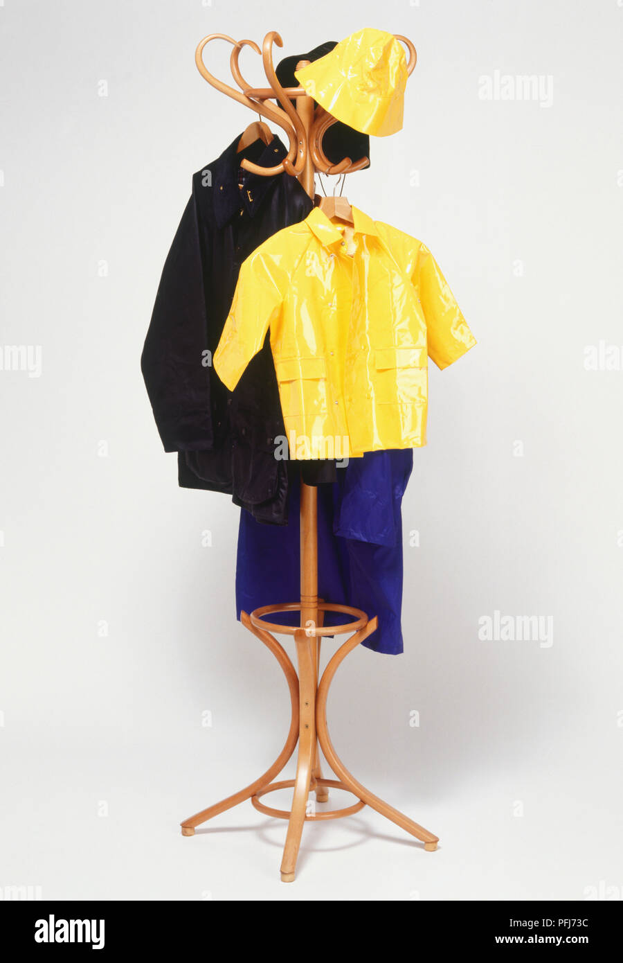 Coats and hats hanging on wooden coat stand, front view. Stock Photo