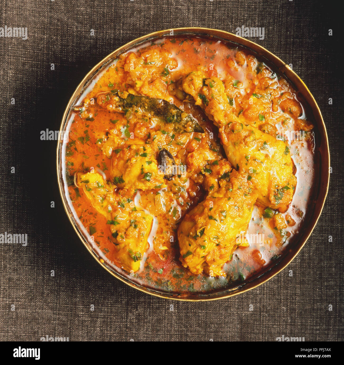 Desi murgh curry, large pan containing chicken wings, herbs, spices and red sauce, overhead view. Stock Photo