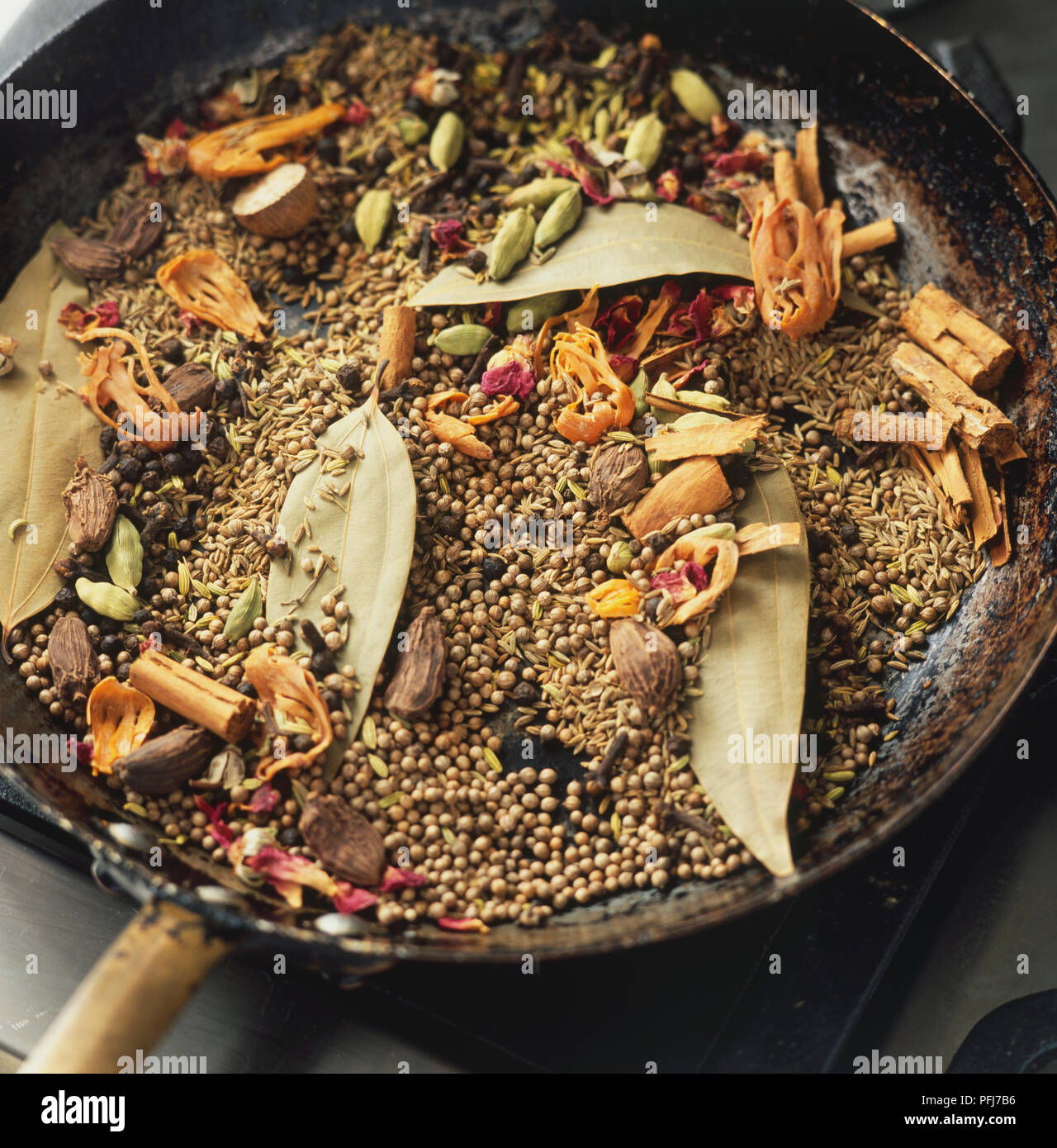 Spice mixture in large pan, leaves, seeds, pods, sticks, overhead view. Stock Photo