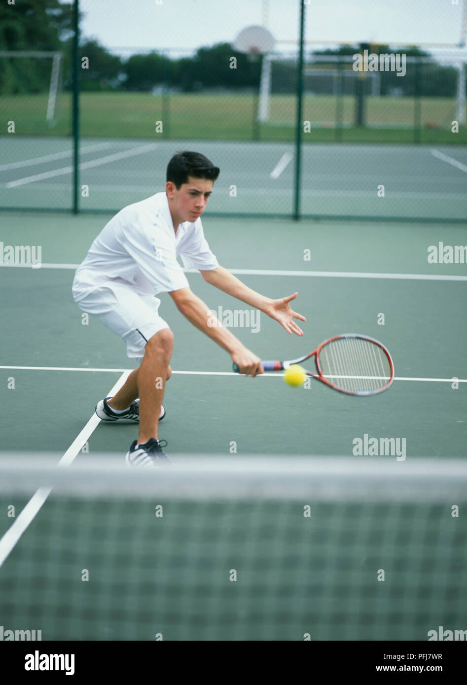 Boy In White Tennis Clothes Bending Forward Holding Racket In Front Of Him Yellow Ball In Air Stock Photo Alamy
