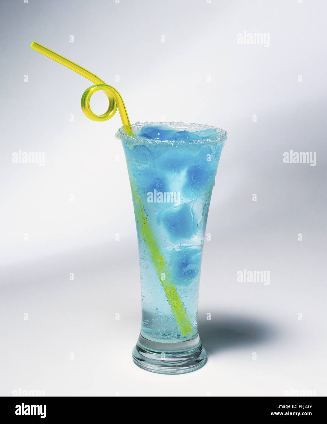 Tall glass of water with blue ice cubes and a curly yellow plastic straw Stock Photo
