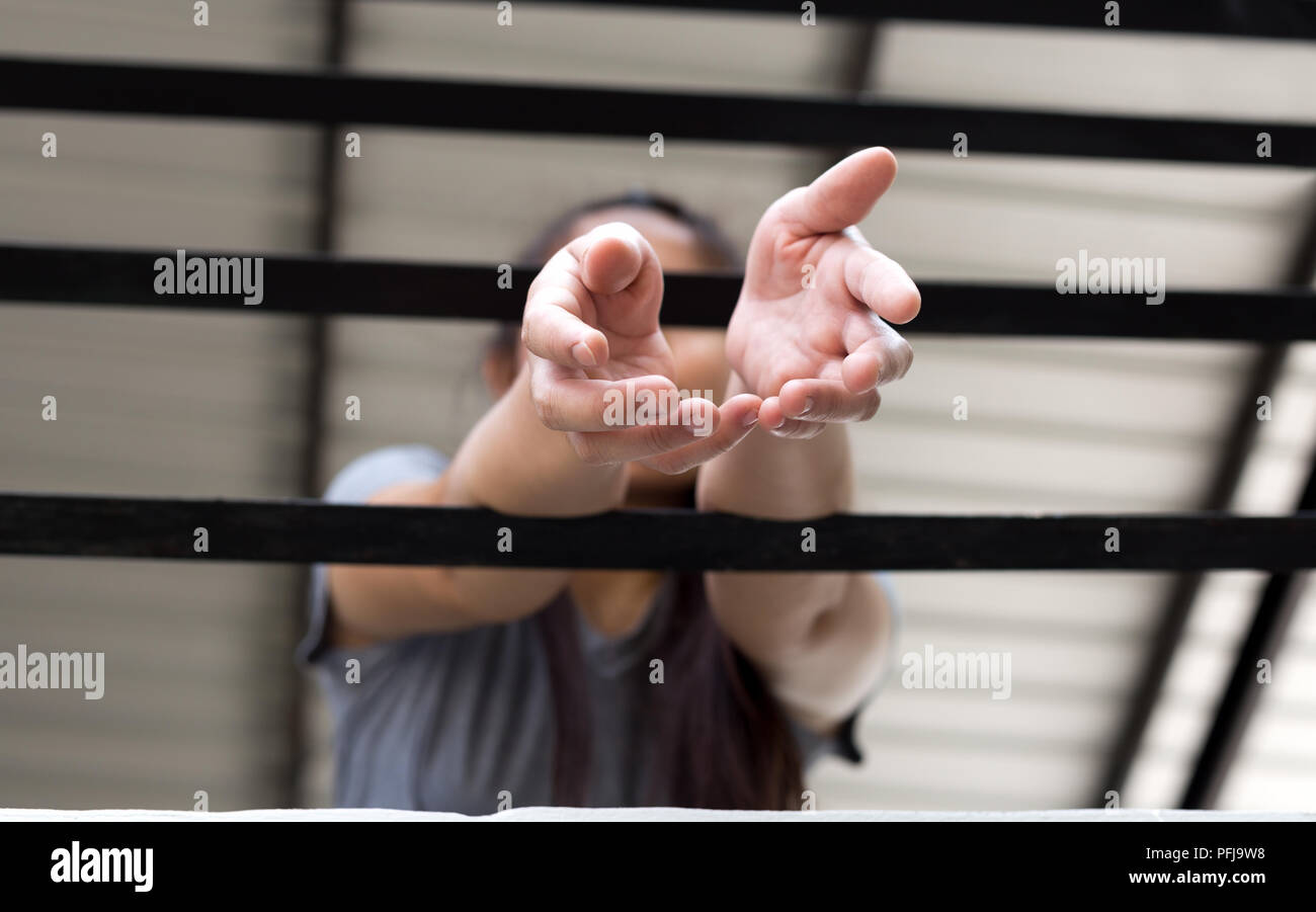 Young woman victim hand reach out for help from a metal bars Stock Photo