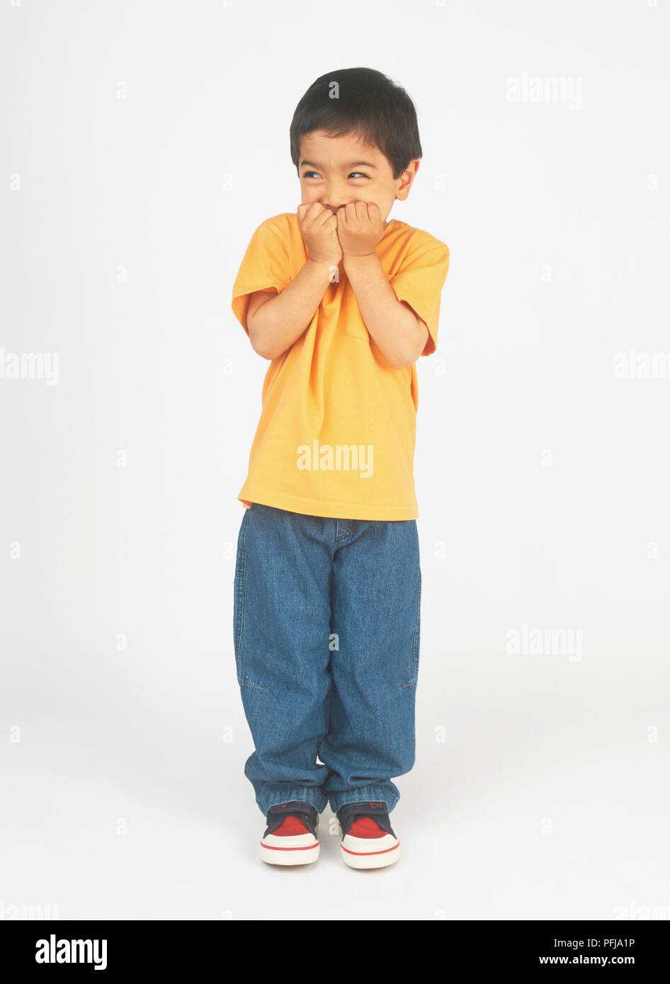 Boy holding his hands to his mouth, looking away Stock Photo