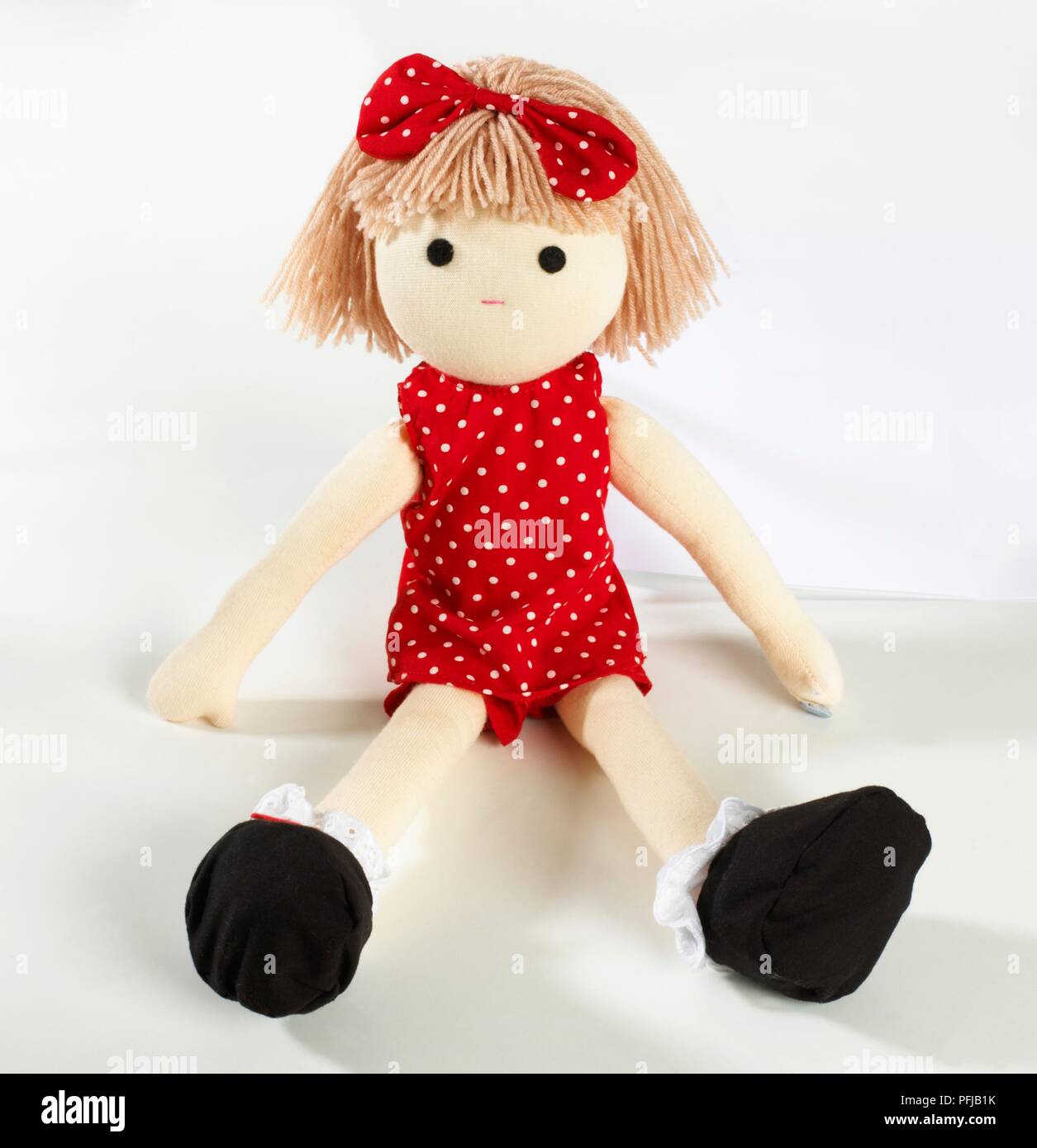 Rag dool wearing red polka dot dress and bow on head Stock Photo