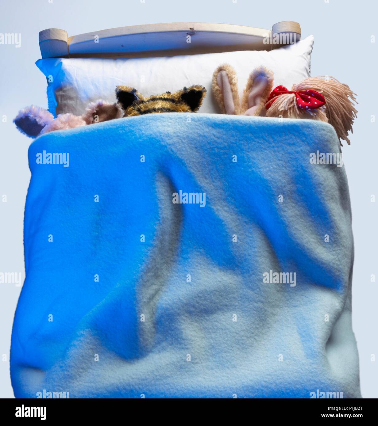 Soft toys tucked in under a blanket Stock Photo Alamy