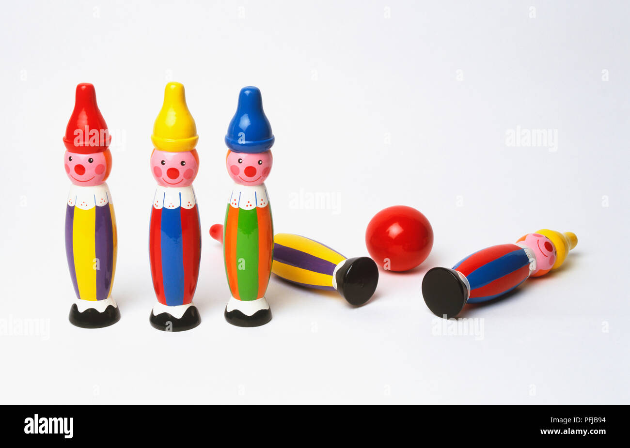 Five colourfully painted bowling pins, two of them knocked down by red