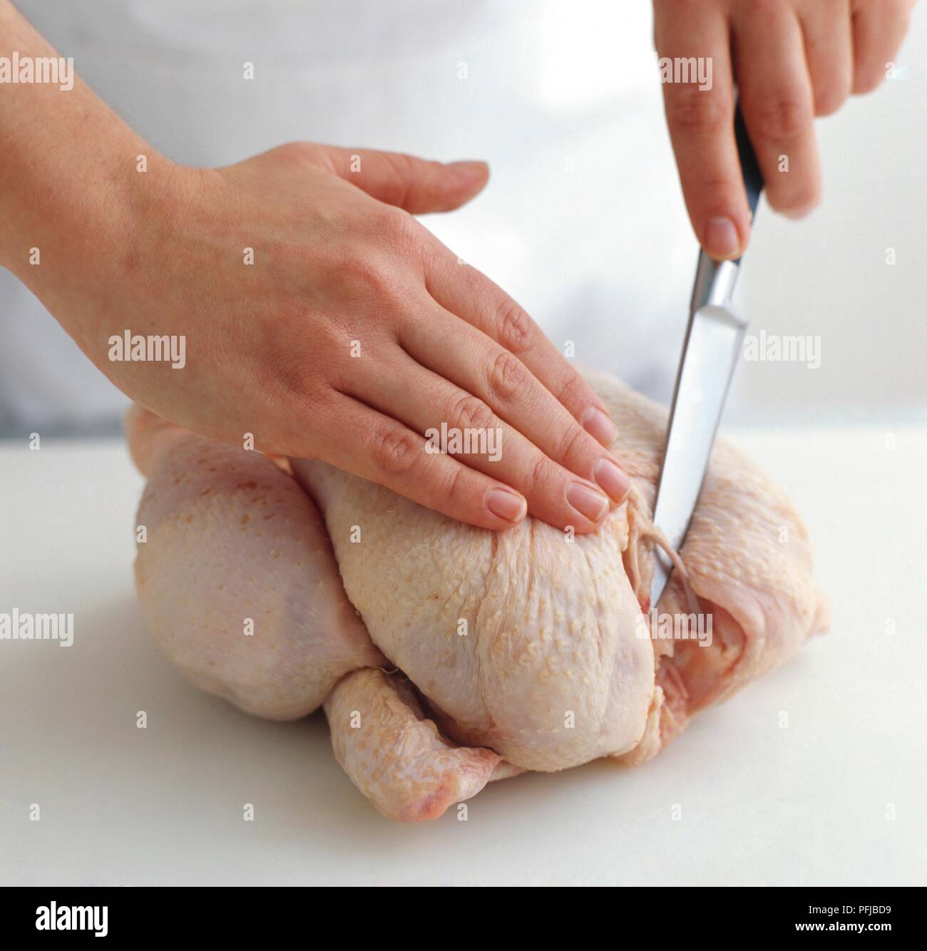 Using sharp knife to expose wishbone of chicken, closeup Stock Photo