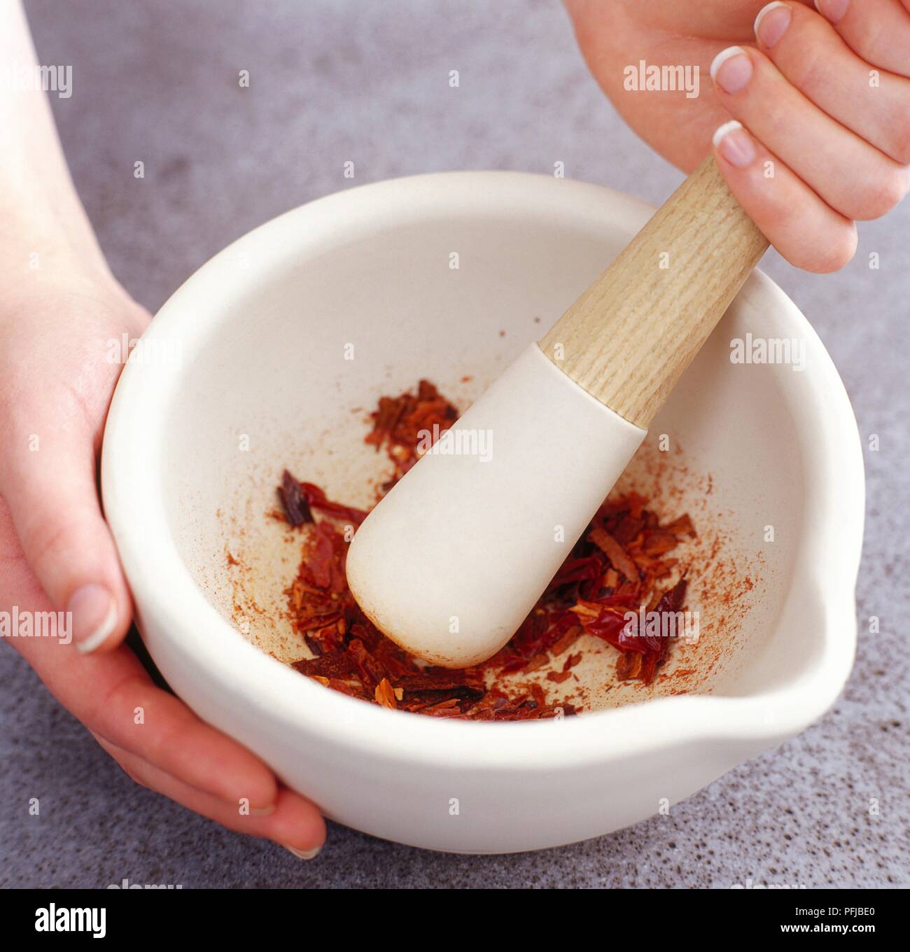 Using a mortar and pestle to grind chillies, closeup Stock Photo Alamy