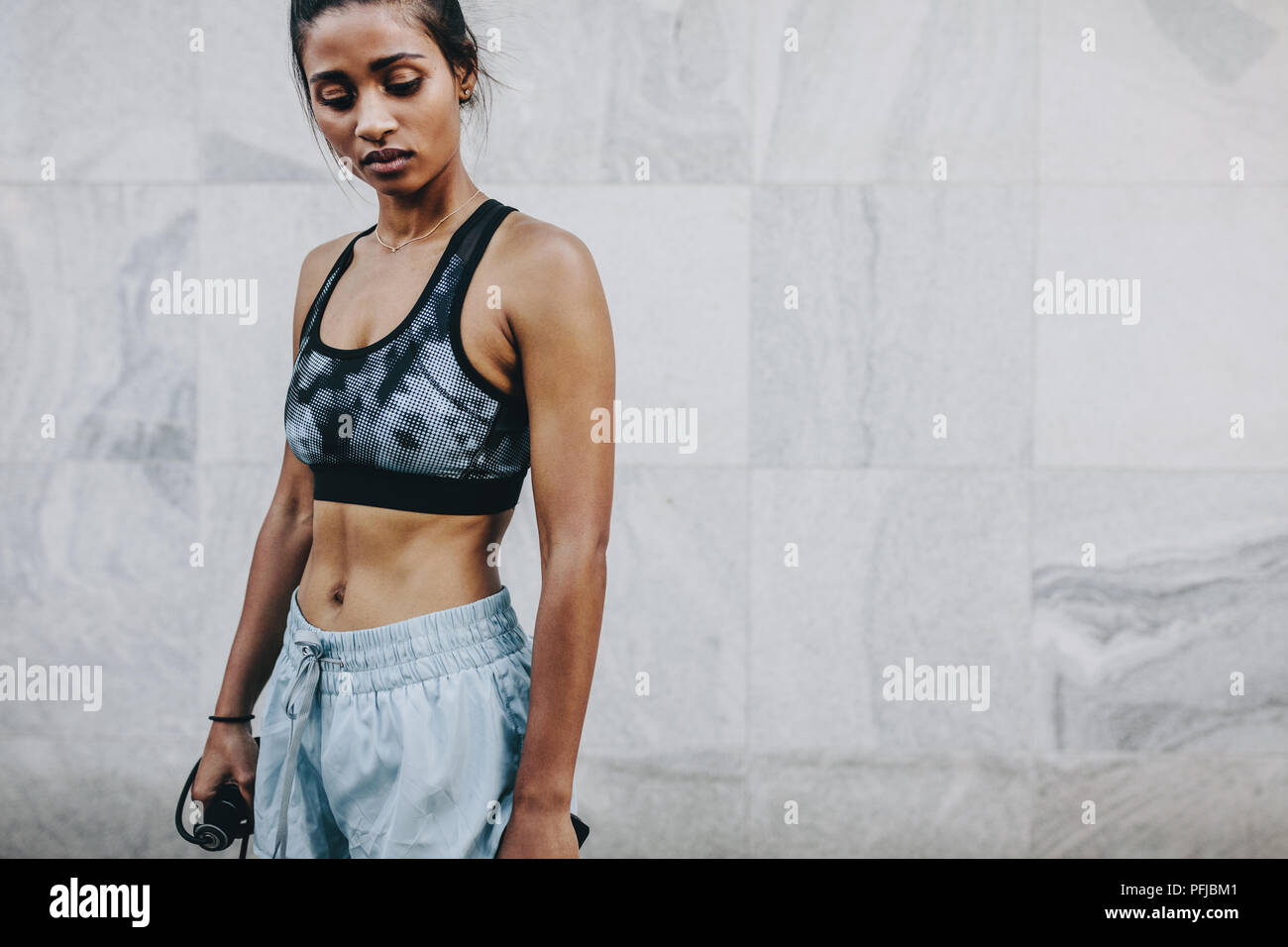 Female athlete in training clothes doing workout holding a skipping