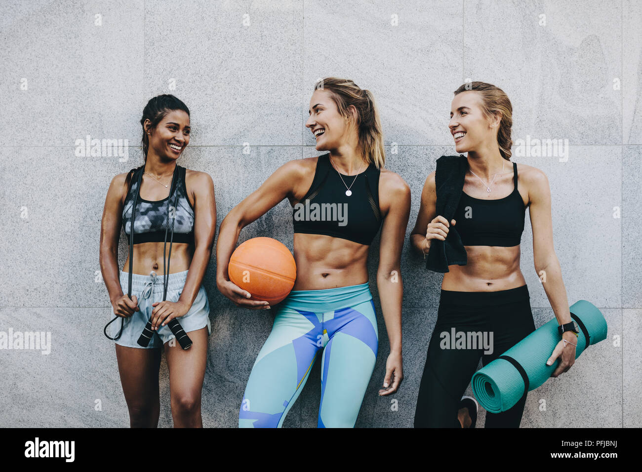 Smiling women athletes in fitness clothes relaxing after workout