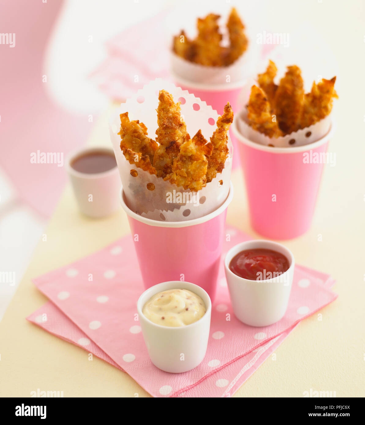 https://c8.alamy.com/comp/PFJC6X/chicken-coated-in-crumbs-made-of-crisps-served-in-pink-plastic-cups-next-to-bowls-of-tomato-ketchup-and-mayonnaise-on-pink-napkins-PFJC6X.jpg