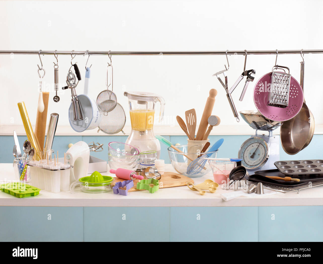 Various cooking and baking utensils on shelf and hanging from rail Stock Photo
