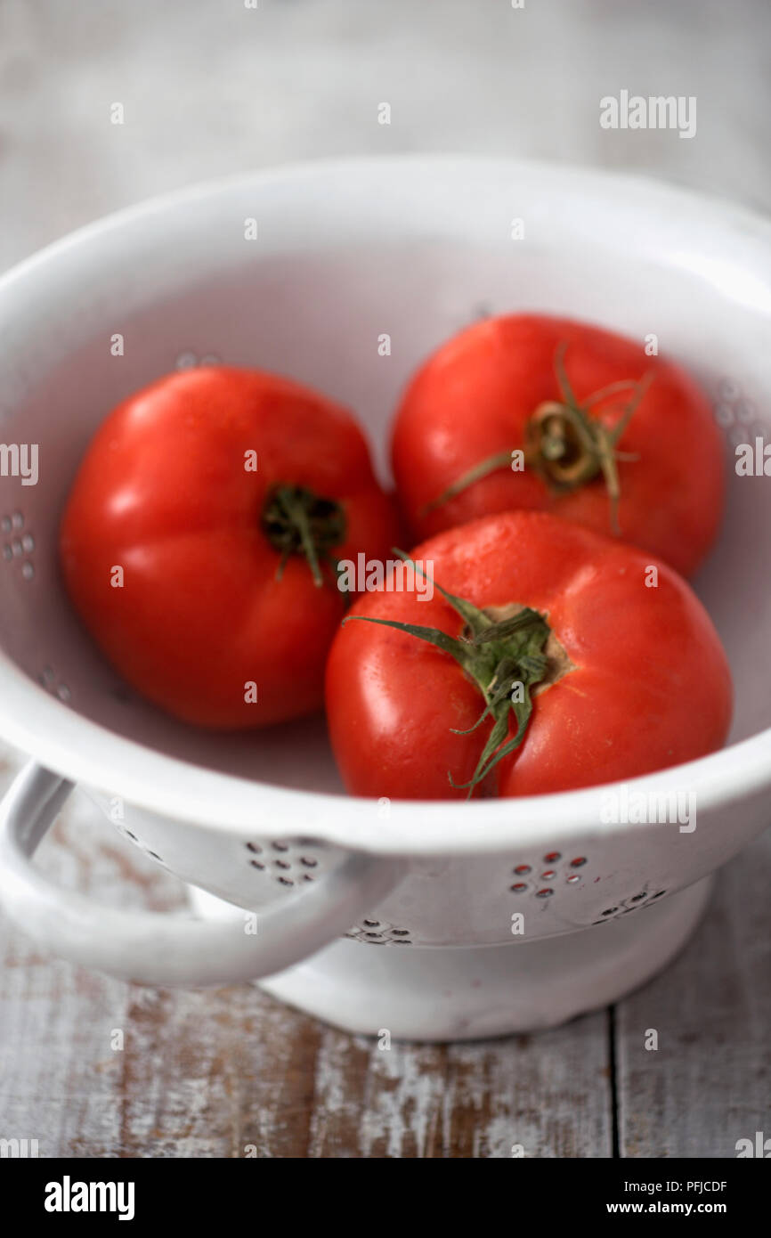 Three beefsteak tomatoes in colander, close-up Stock Photo