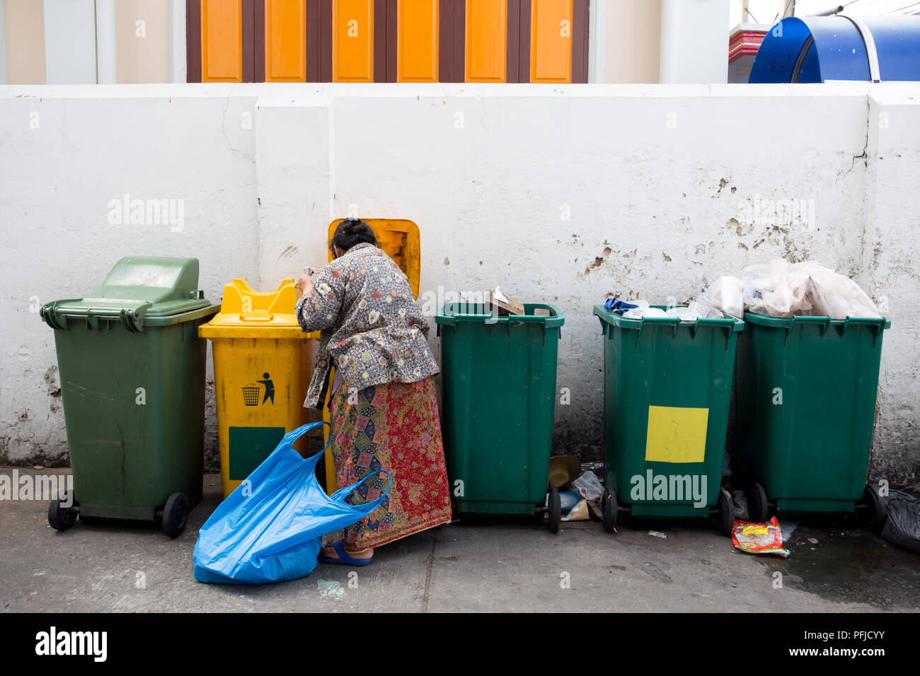homeless woman is searching the trash in a trash bin on street Stock Photo Alamy