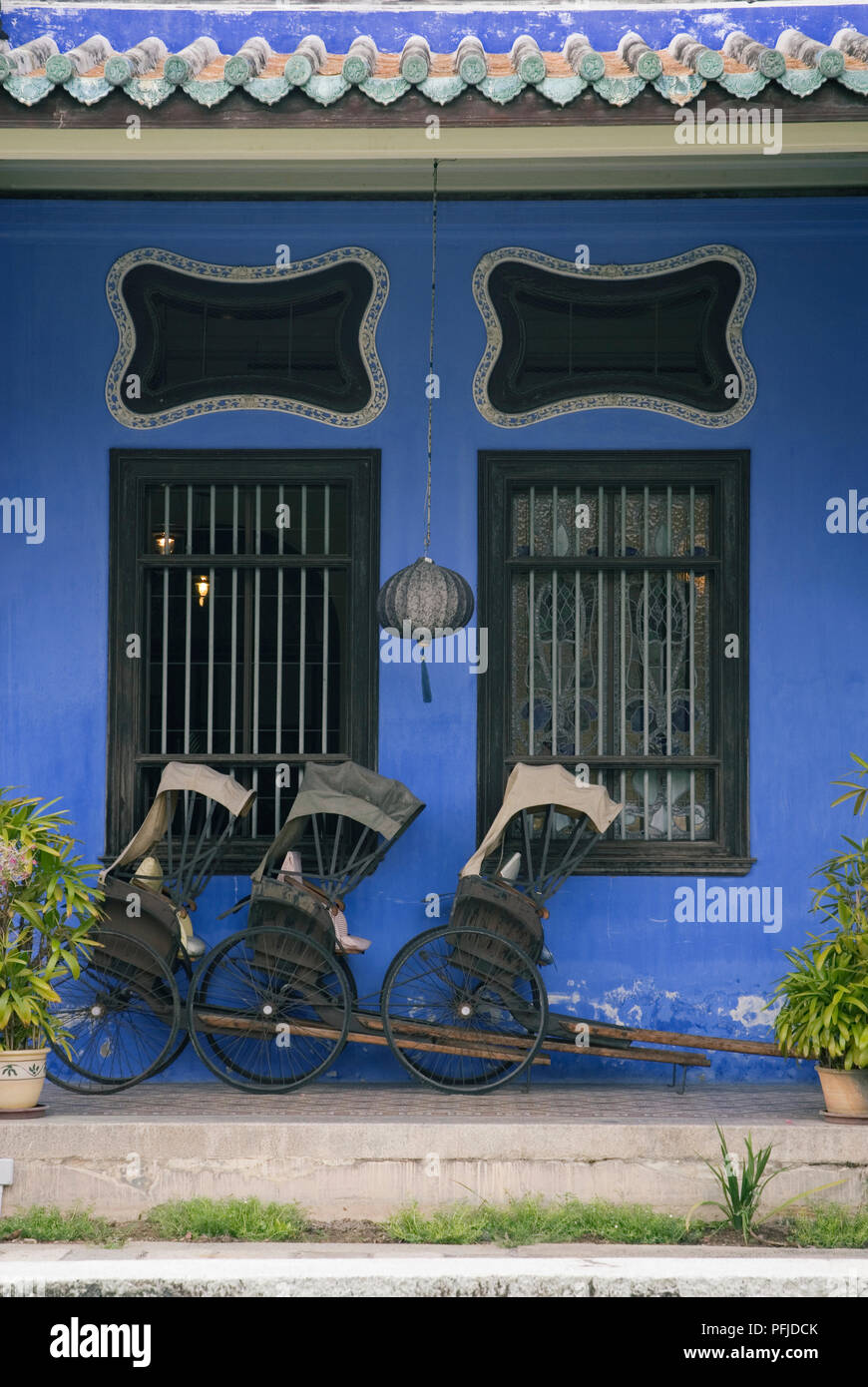 Malaysia, Penang, Georgetown, Chong Fatt Tze Mansion, blue facade detail with rickshaws parked outside Stock Photo