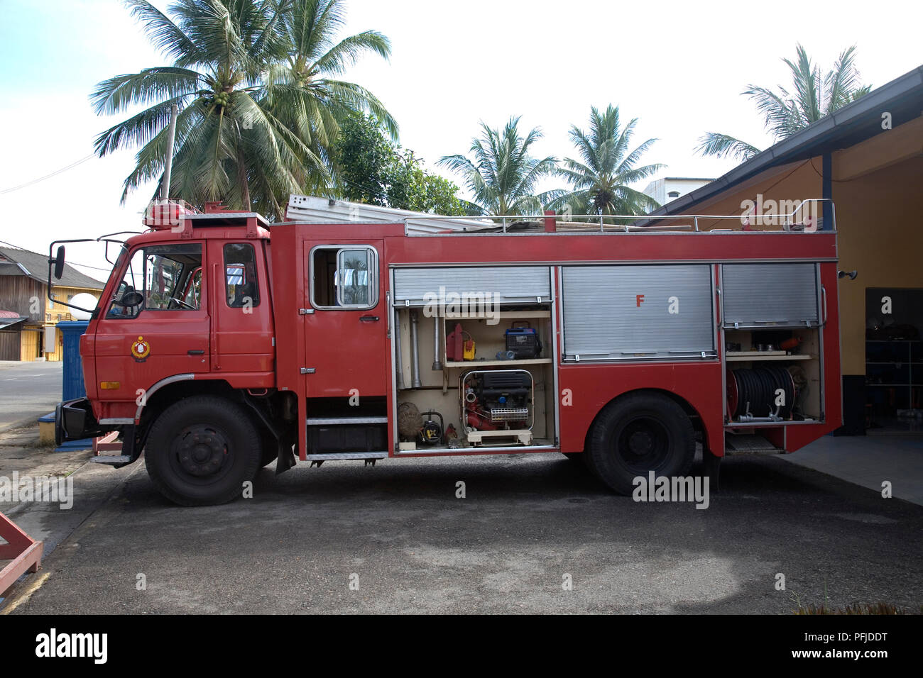 Malaysia, fire engine parked outside building near palm trees, side view Stock Photo
