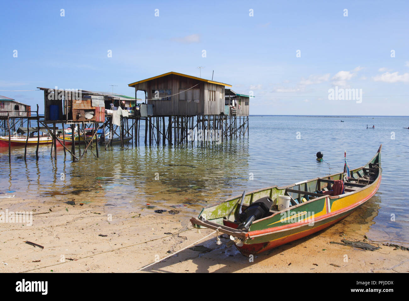 Malaysia, Sabah, Mabul Island, stilt houses in the sea, and a boat moored on the beach nearby, close-up Stock Photo