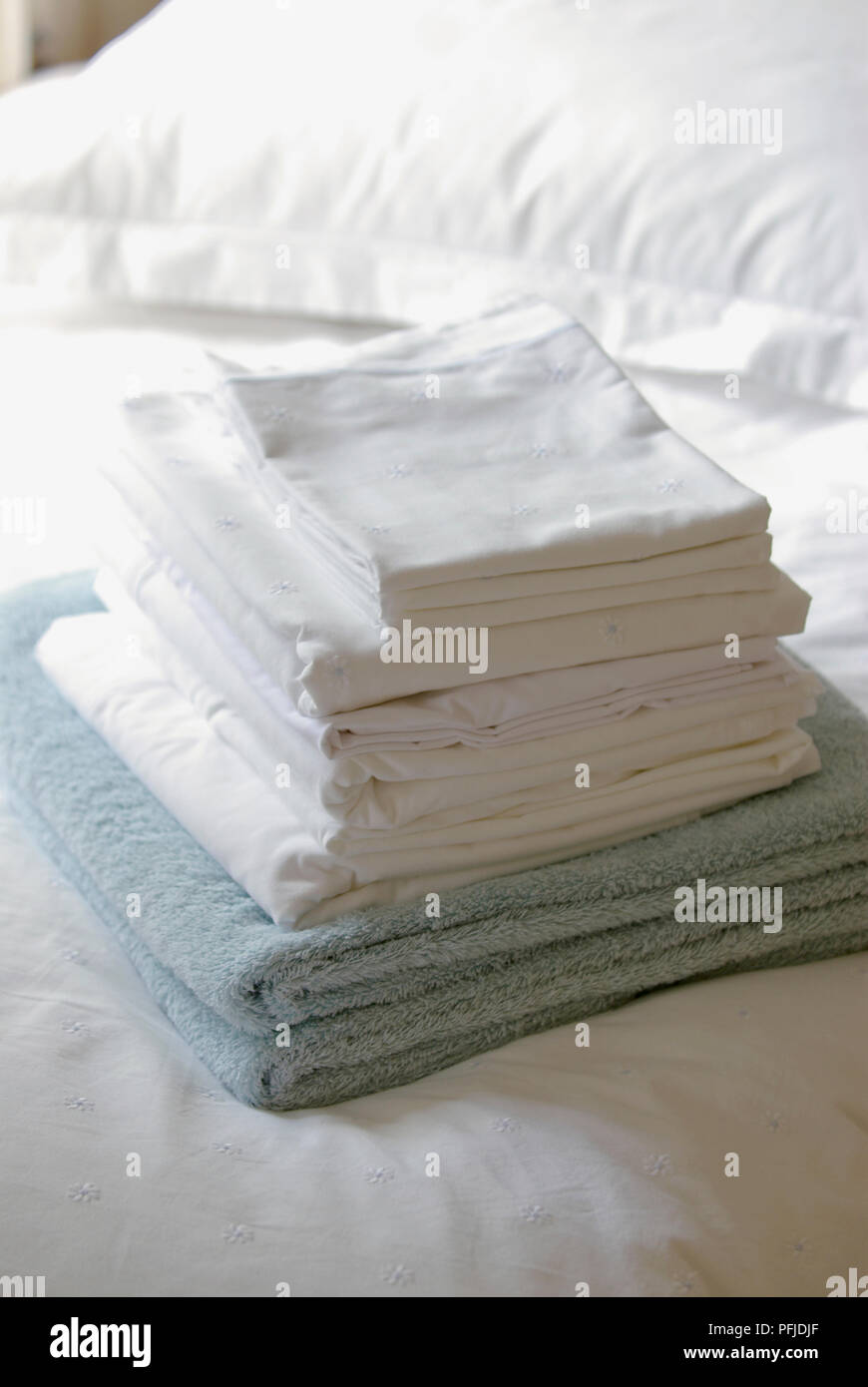 Pile of folded towels and bedclothes, on bed Stock Photo