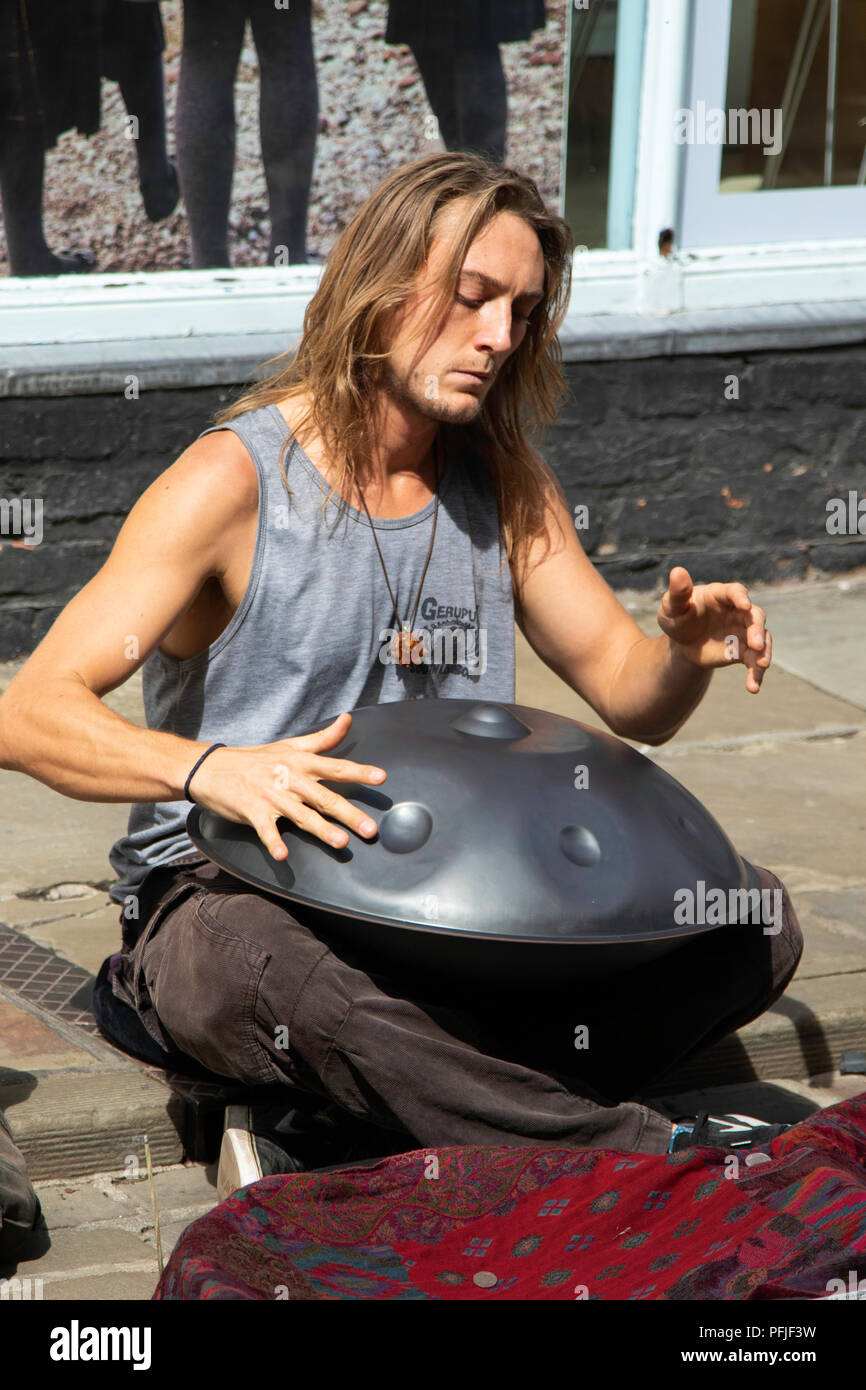 Street Busker sat on a street in York playing a Hang Drum, North Yorkshire, England, UK. Stock Photo