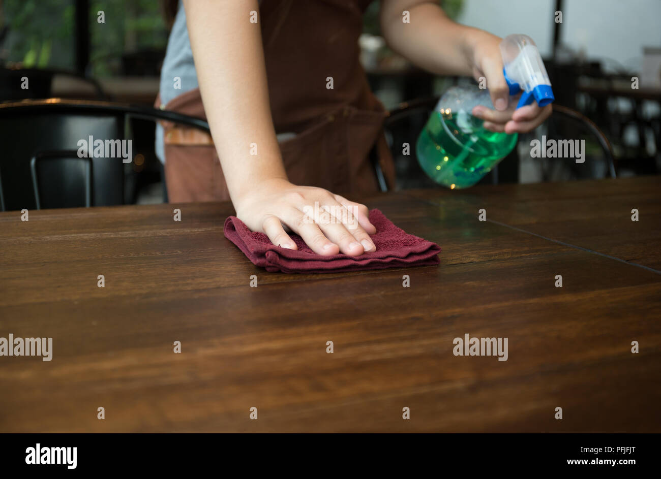 Waitress cleaning the table with spray disinfectant in a restaurant ...