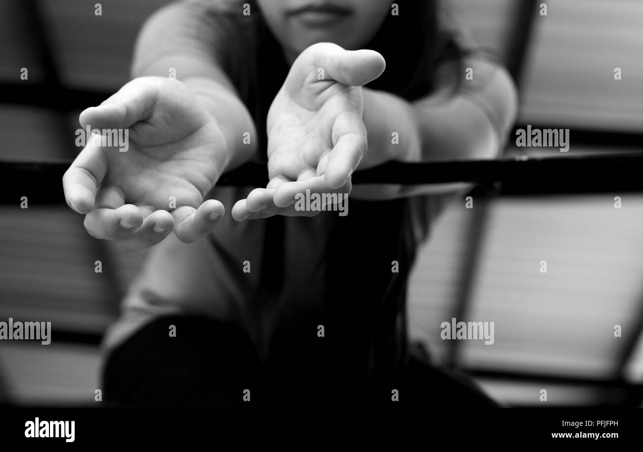 Young woman victim hand reach out for help from a metal bars in black and white Stock Photo