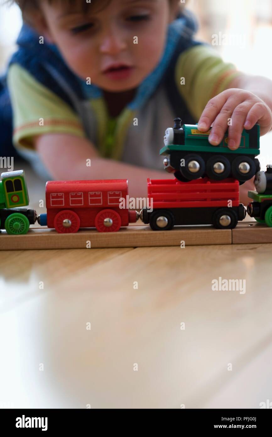 Boy lying on floor playing with train set Stock Photo - Alamy