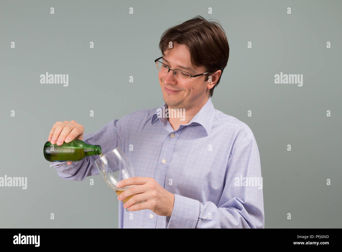 a young man pouring lager beer from green bottle to glass Stock Photo