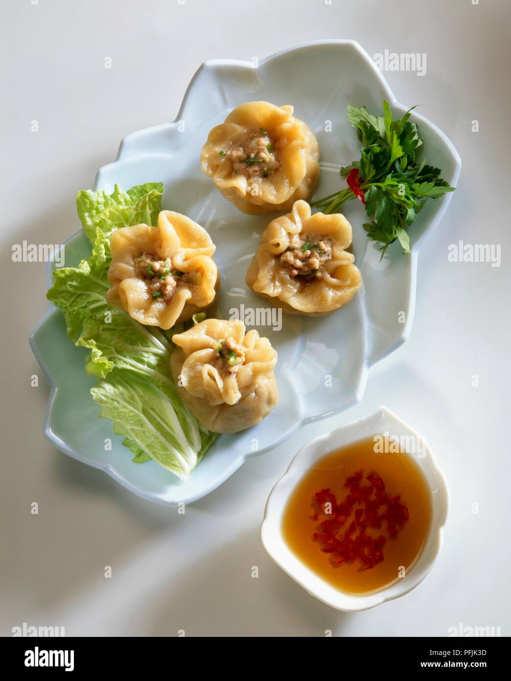 Steamed openfaced Dumplings (Shao Mai) served with cabbage leaf, herbs