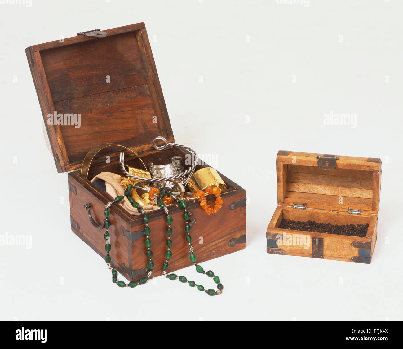 Jewellery spilling out of open wooden chest, second wooden chest containing Black Peppercorns