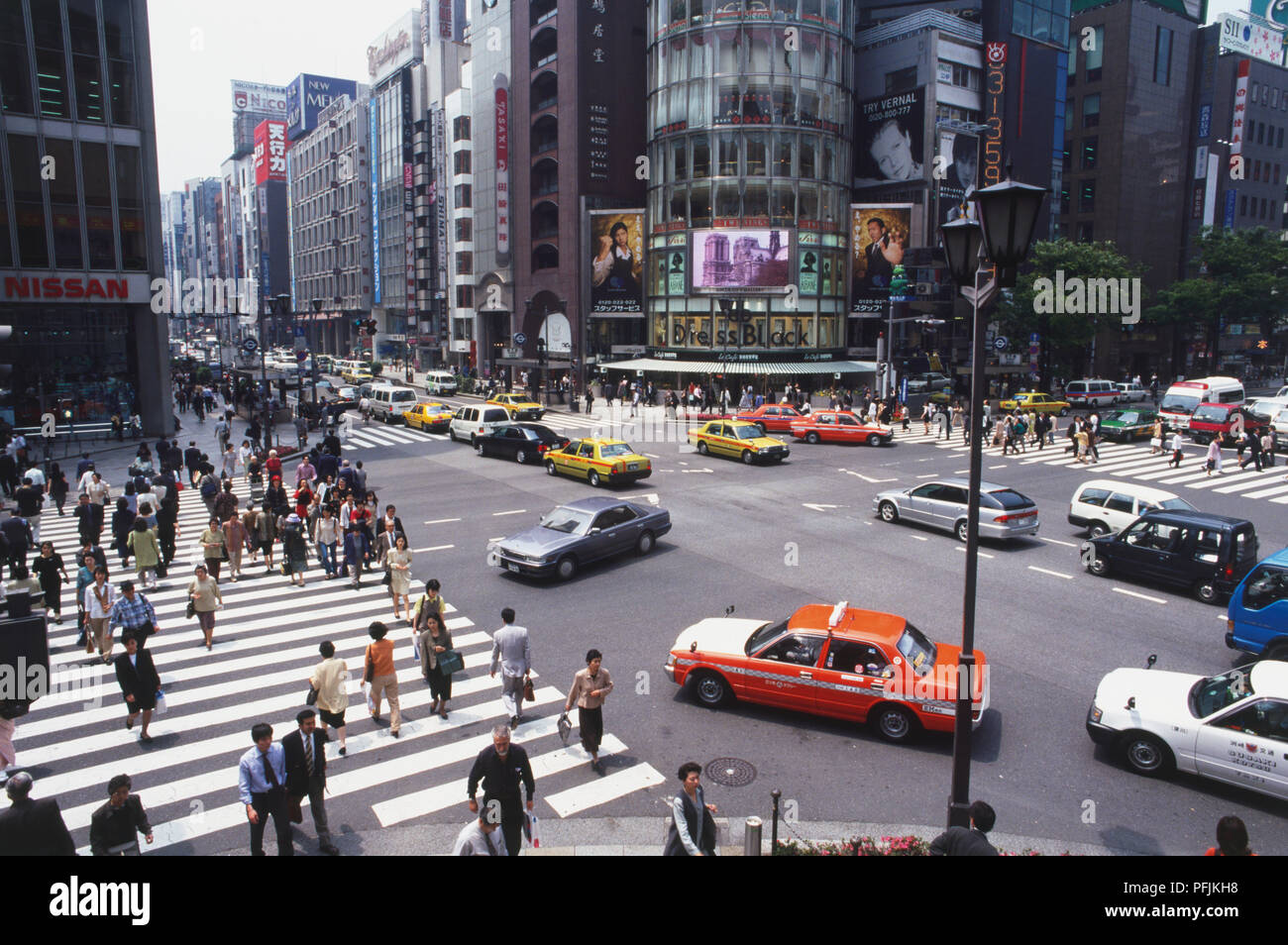 Japan, Tokyo, Centre, pedestrians and cars at Ginza-Yon-chome crossing, dominated by rounded glass front of San'ai Building, high angle view. Stock Photo