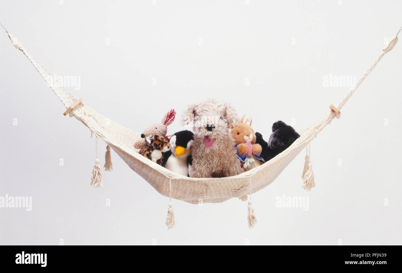 Selection of soft toy animals resting on hanging hammock, front view