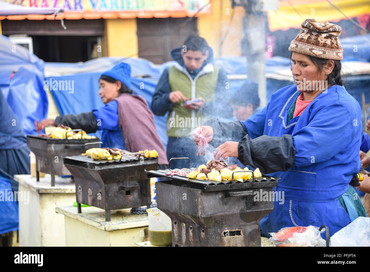A lady cooks meat and potatoes on a street food stall outside the