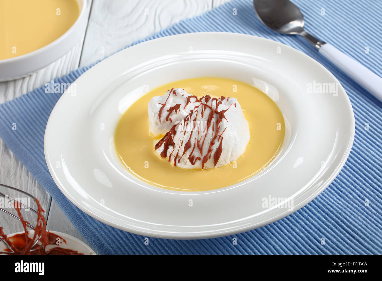 a floating island or ile flottante, consisting of meringue floating on creme anglaise and drizzled with chocolate ganache, authentic recipe, ingredien Stock Photo