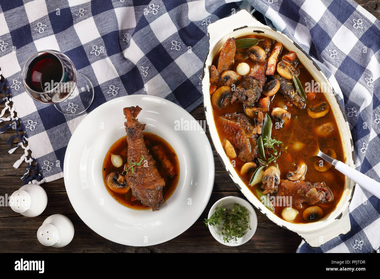 festive dinner recipe - a chicken rooster stewed in red wine with spice, herbs, authentic french recipe - coq au vin in a large oval rustic Dutch oven Stock Photo