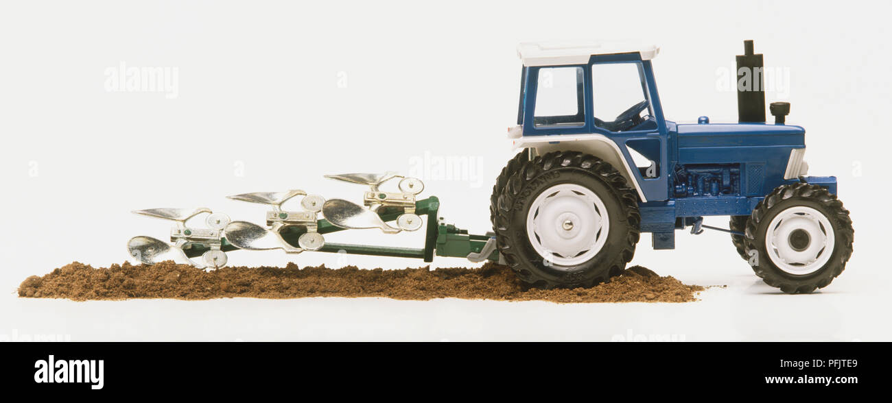 Toy tractor with plough, side view Stock Photo