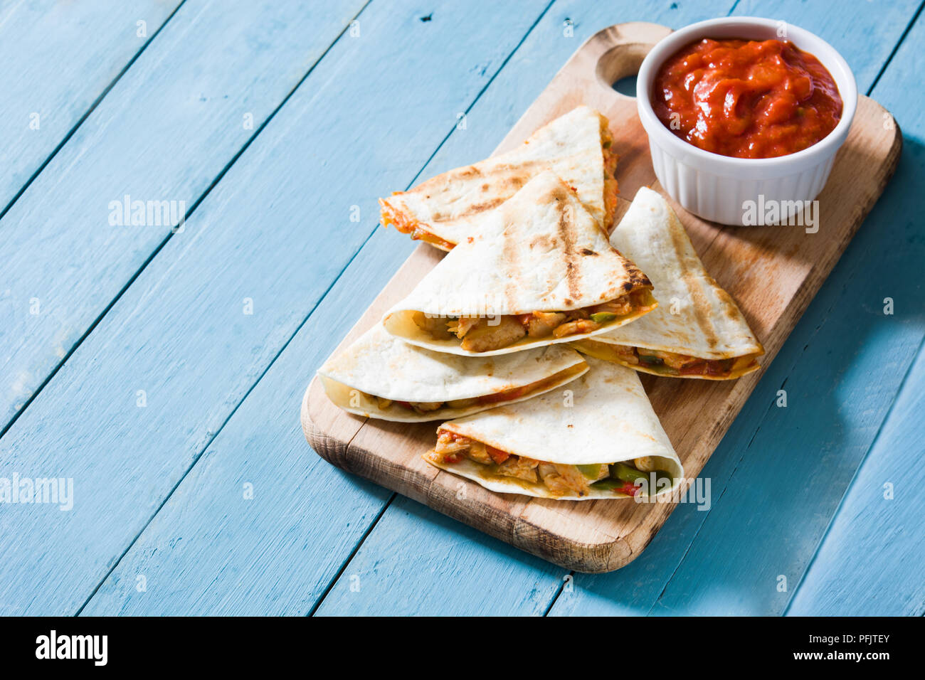 Mexican quesadilla with chicken, cheese and peppers on blue wooden table. Stock Photo