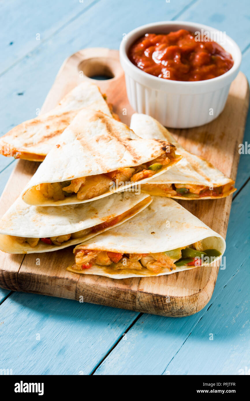 Mexican quesadilla with chicken, cheese and peppers on blue wooden table. Stock Photo