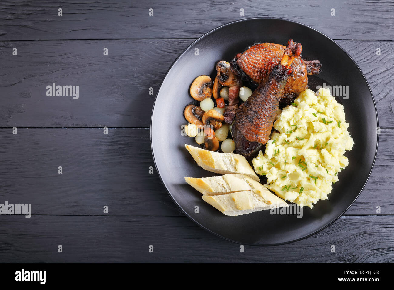 a portion of classic French rooster stew served on black plate with potato puree and bread, horizontal view from above Stock Photo