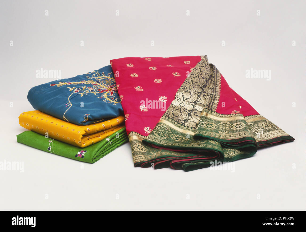 Colourful pile of folded embroidered Asian fabrics Stock Photo
