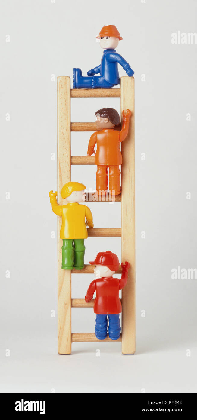 Four plastic toy figurines on steps of a miniature ladder Stock Photo