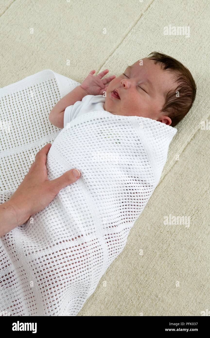 Swaddling a baby boy in a cellular blanket, close-up Stock Photo