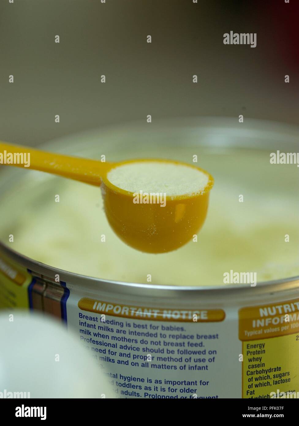 Formula milk in measuring spoon and in can behind Stock Photo