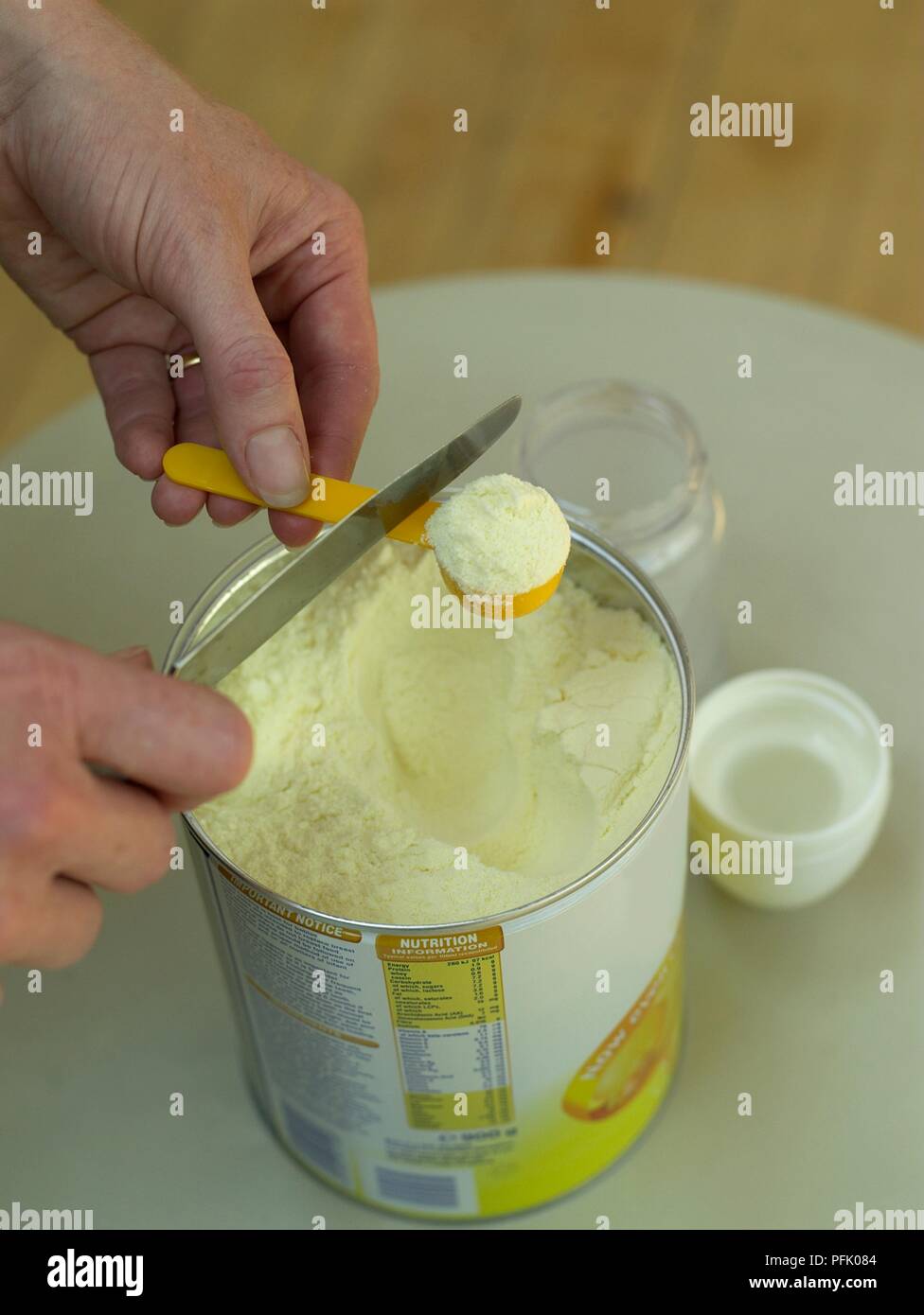 Woman's hands scraping off excess formula from measuring spoon, close-up Stock Photo