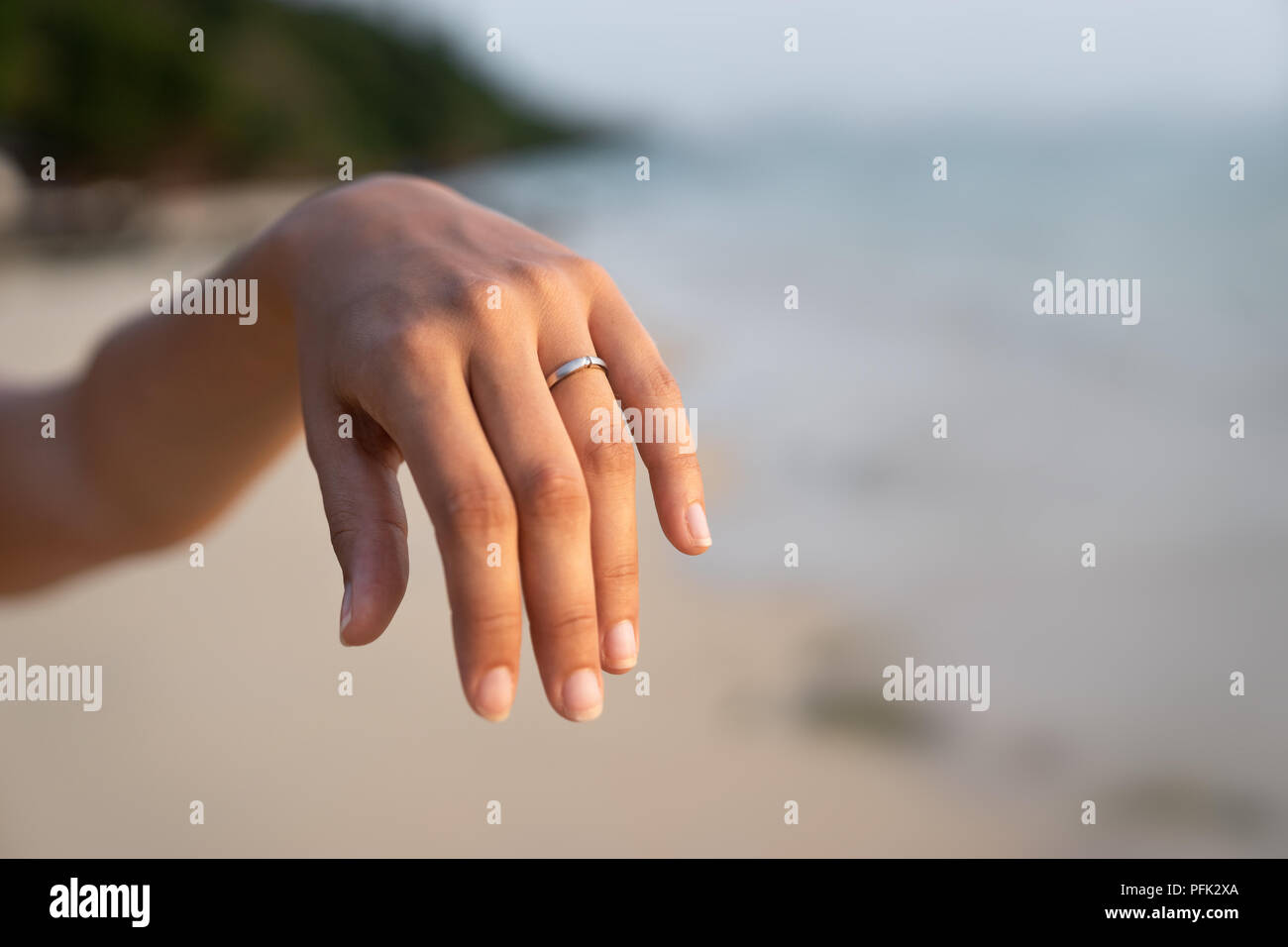 silver engagement ring on fiancees hand - romantic proposal on beach Stock Photo