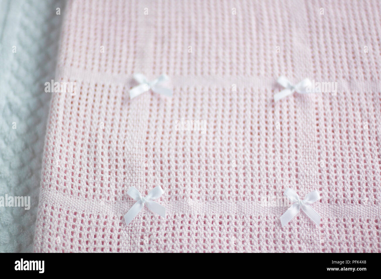 Pink cellular baby blanket with four white bows, close-up Stock Photo