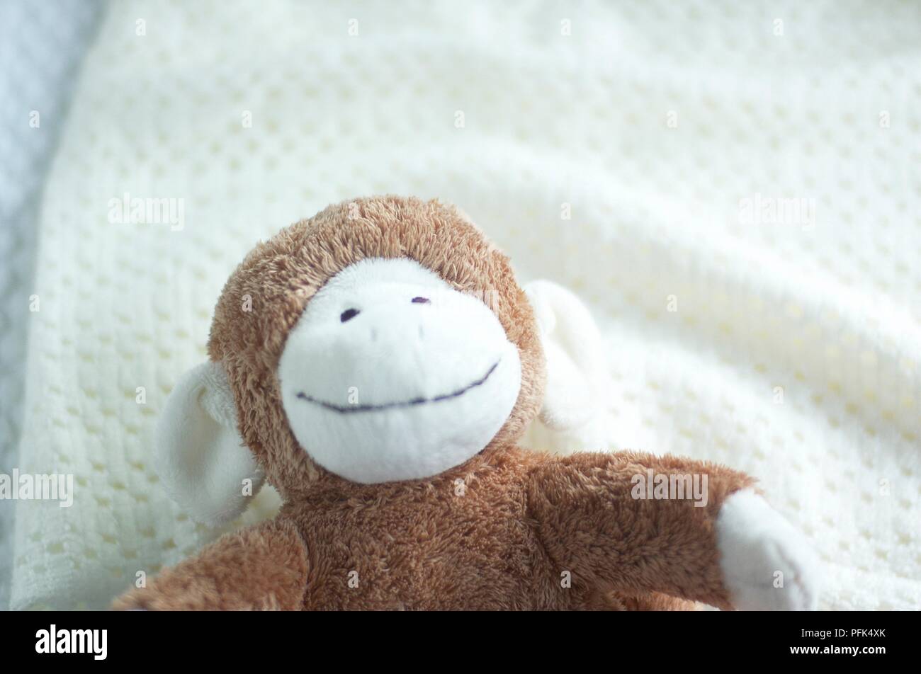 Stuffed monkey toy on white blanket, close-up Stock Photo