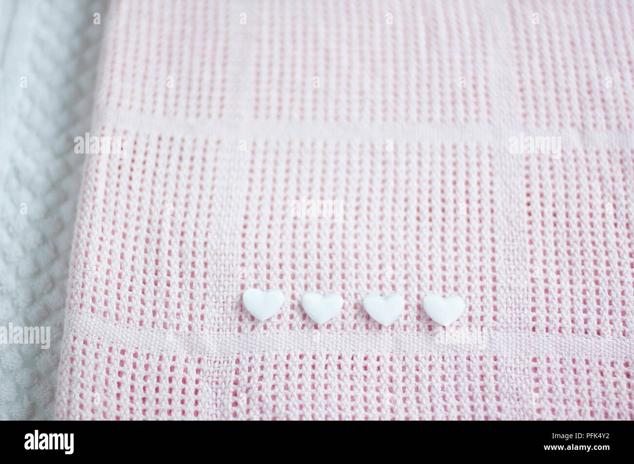 Four white hearts on pink cellular blanket, close-up Stock Photo