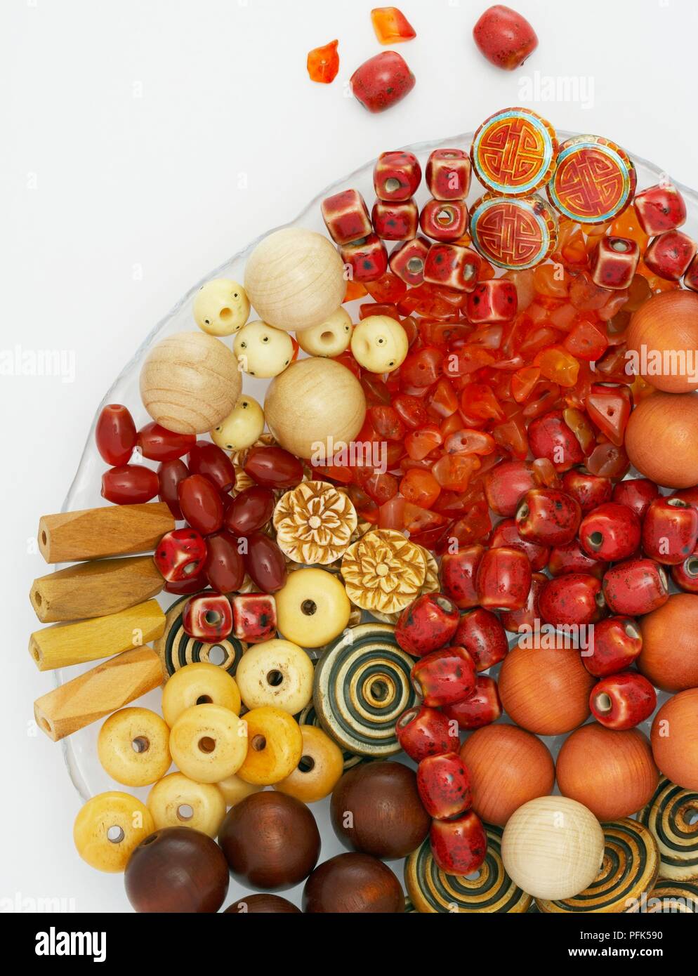 Assortment of differently shaped wood, bone, stone and ceramic beads on plate Stock Photo