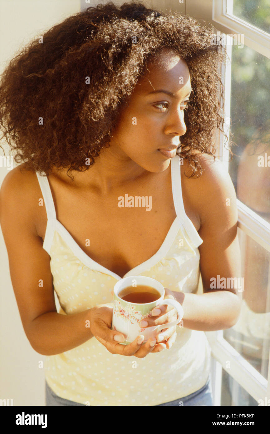 Woman holding cup of tea looking out of window Stock Photo